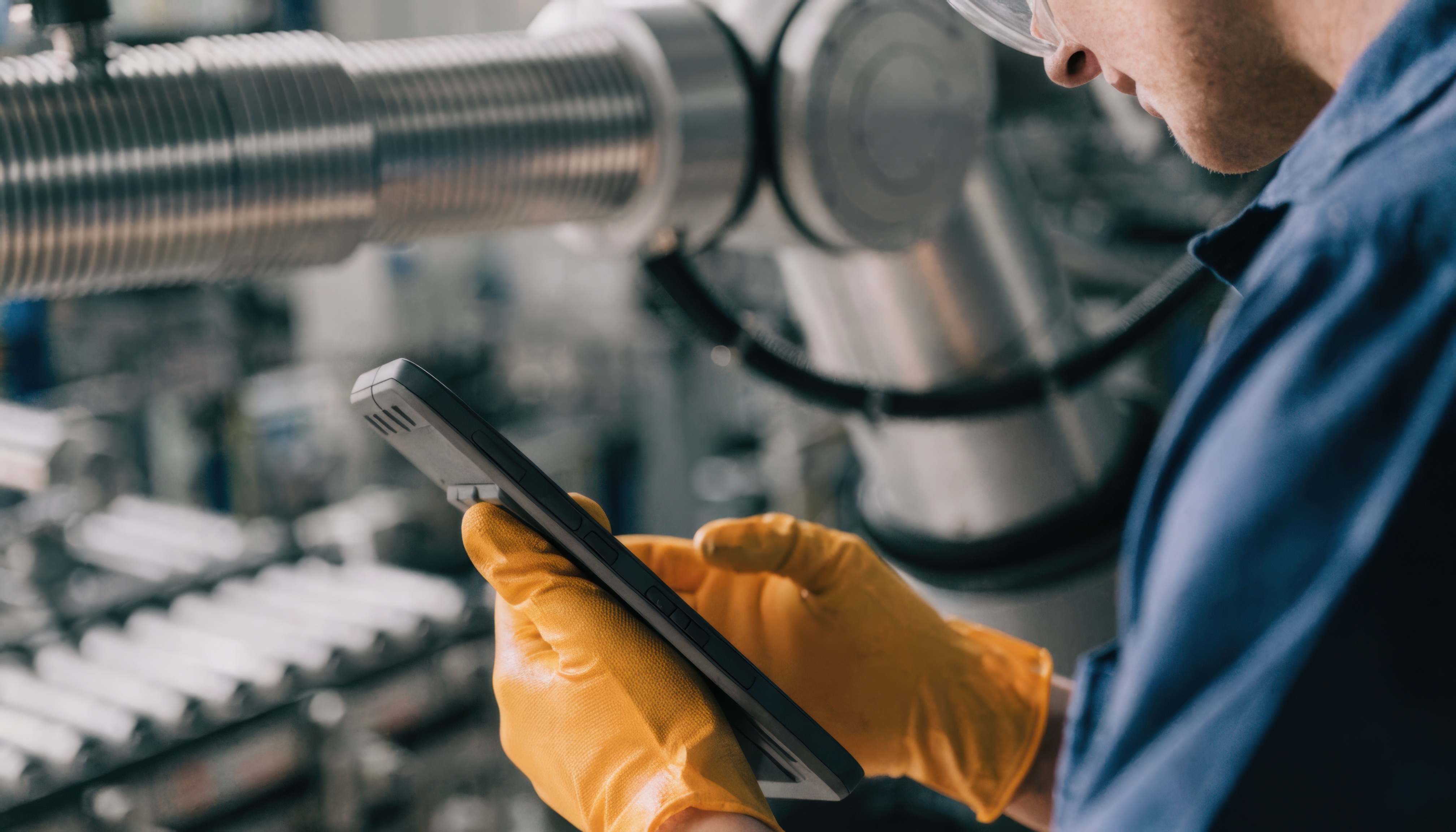Gloved hands holding a tablet at a machine